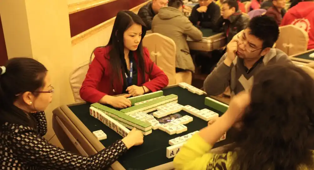 Ihmisiä pelaamassa perinteistä Mahjongia